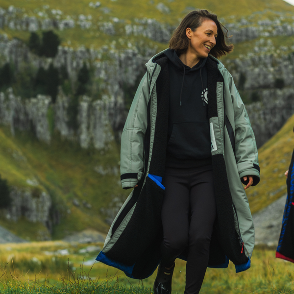 Woman in a long coat walking outdoors with a scenic background